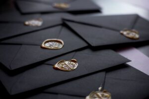 Close-up of stylish black envelopes featuring vintage wax seals, perfect for luxury invitations.
